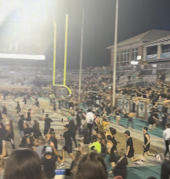 Fans jump over the Brooks Stadium audience barrier while some walked through the open gate to celebrate Coastal football's win against Appalachian State University on Nov. 7.